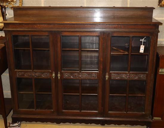 A 1920s carved oak three door bookcase, W.152cm, D.36cm, H.120cm